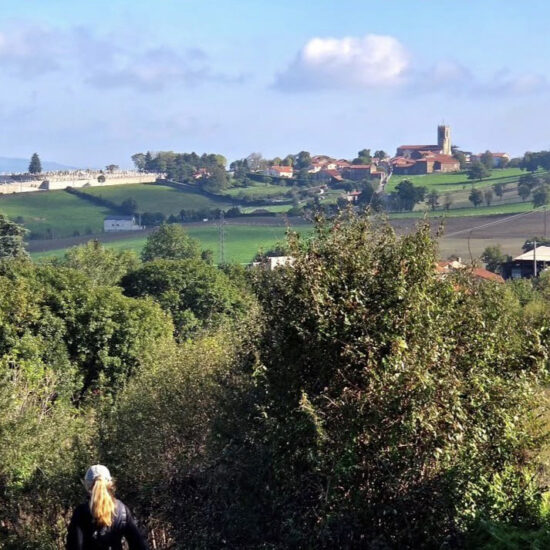 une femme qui se promène en premier plan, un hameau au second plan