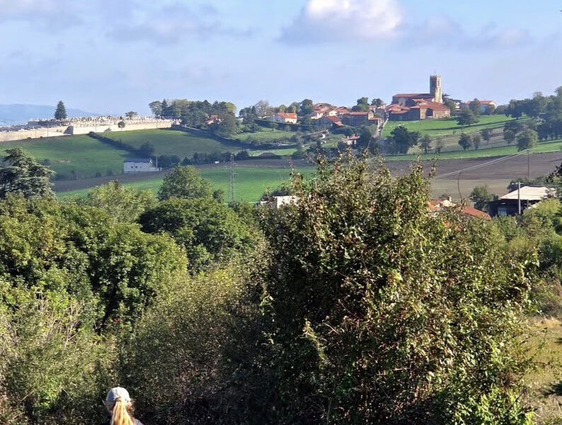 une femme qui se promène en premier plan, un hameau au second plan