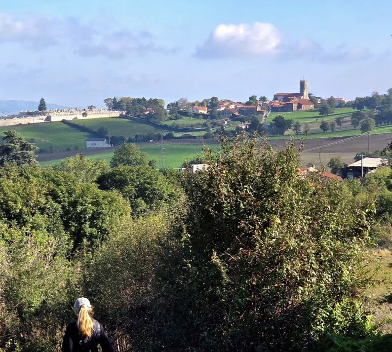 une femme qui se promène en premier plan, un hameau au second plan