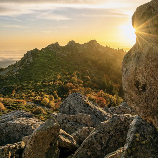 coucher ou levée de soleil avec rocher au premier plan et montagne au second plan