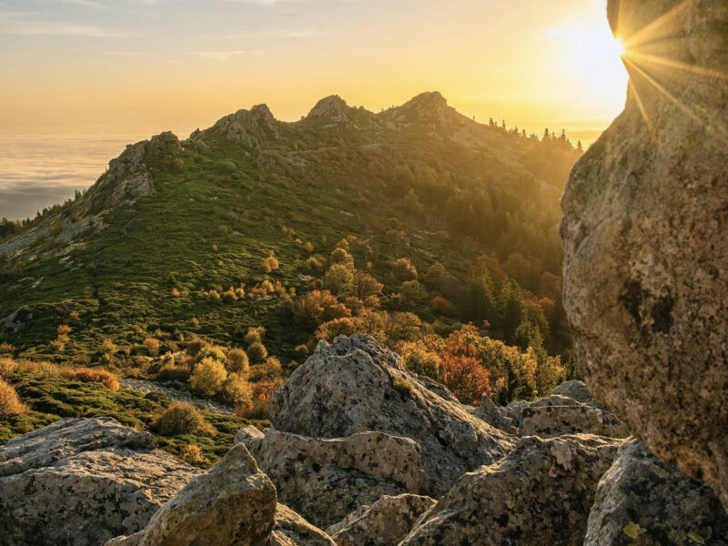 coucher ou levée de soleil avec rocher au premier plan et montagne au second plan