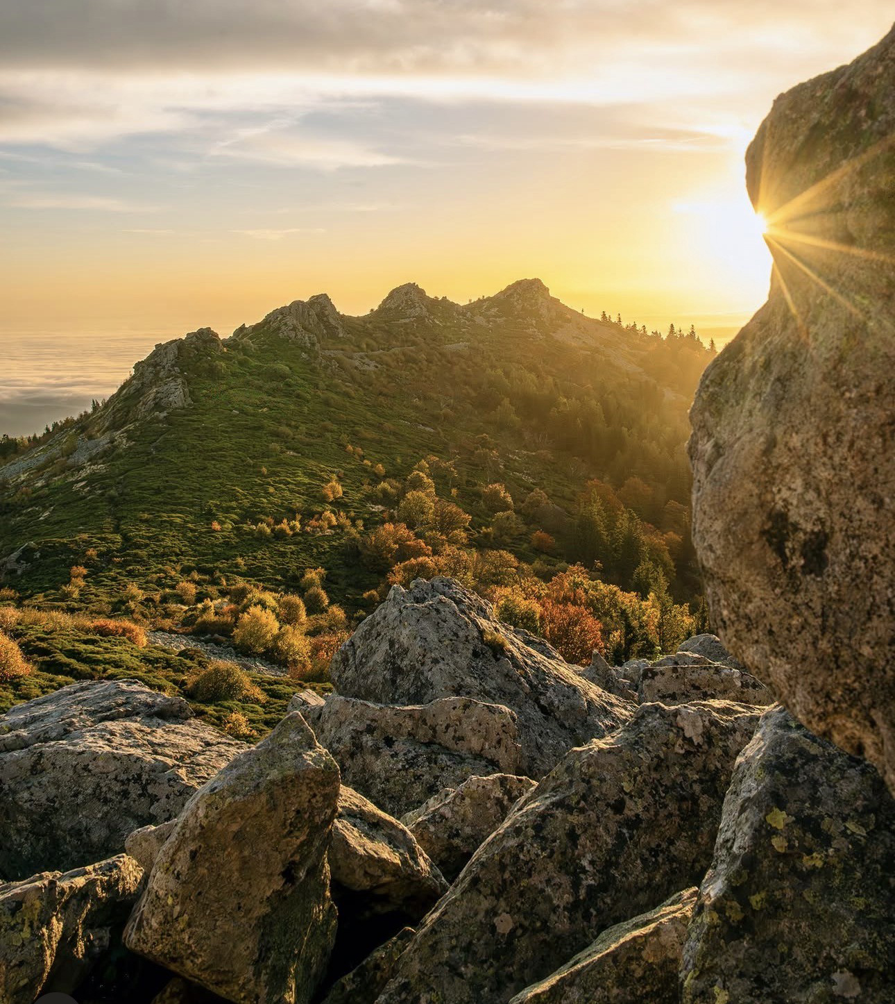 coucher ou levée de soleil avec rocher au premier plan et montagne au second plan