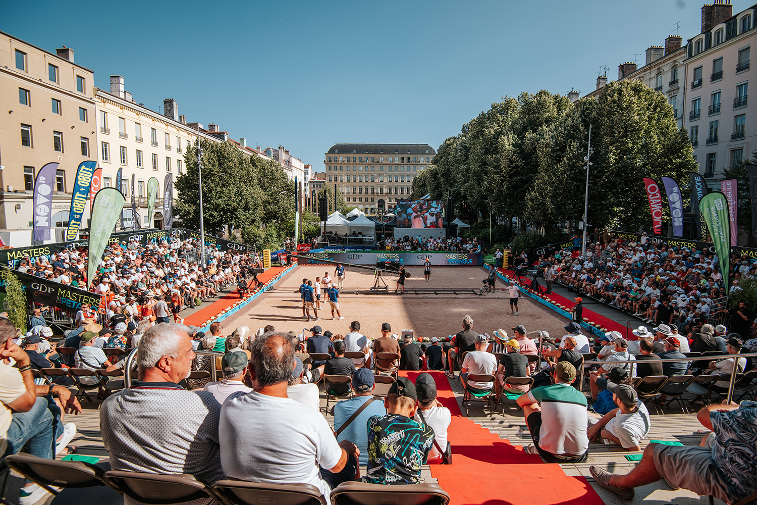 terrain de pétanque avec joueurs et foule sur une place